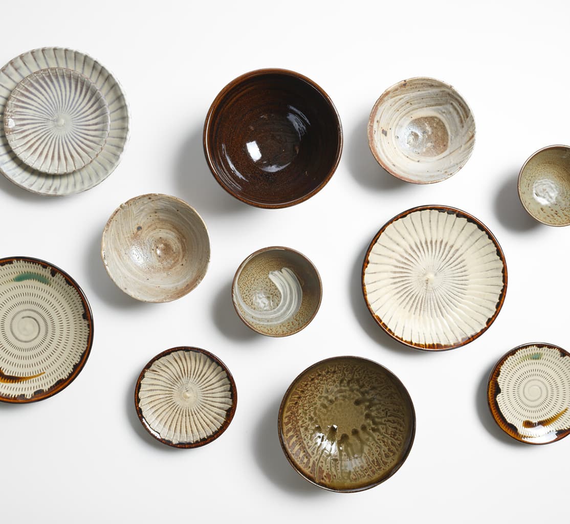 A group of Takatori ware and Koishiwara ware plates and bowls from Japan House London.